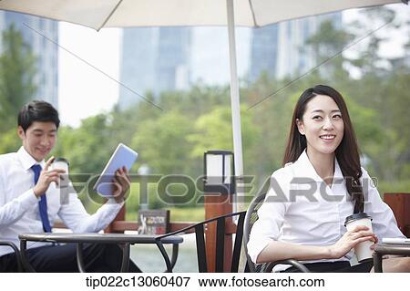Stock Photo - a business woman working while having a coffee. Fotosearch