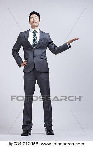 Stock Photo - a businessman standing with something in his one hand. Fotosearch