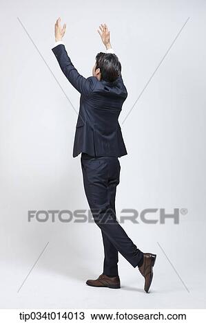Stock Image - a businessman walking with two hands up. Fotosearch