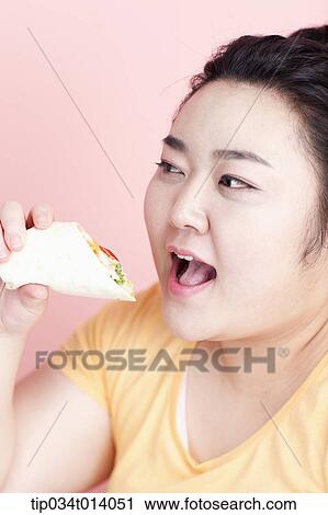 Stock Image - a chubby woman about to eat sandwich wrap. Fotosearch