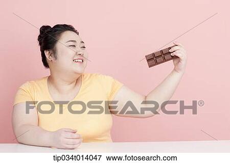 Stock Photo - a chubby woman staring at chocolate. Fotosearch