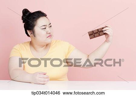 Stock Photograph - a chubby woman staring at chocolate. Fotosearch