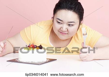 Stock Image - a chubby woman with a cake in front of her. Fotosearch