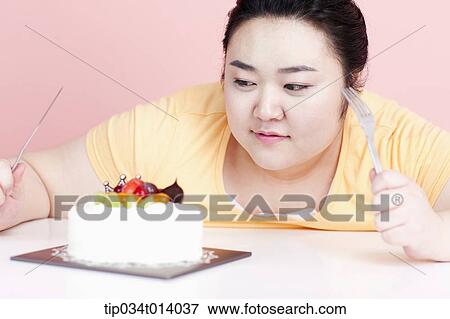 Stock Photo - a chubby woman with a cake in front of her. Fotosearch