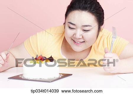 Stock Photo - a chubby woman with a cake in front of her. Fotosearch