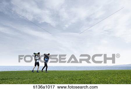 a couple hiking on a grass field View Large Photo Image Stock Photo - a couple hiking on a grass field. Fotosearch