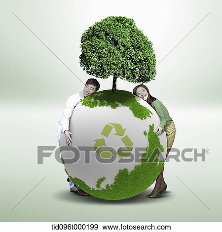 Stock Photo - a couple leaning on a green globe with a tree. Fotosearch