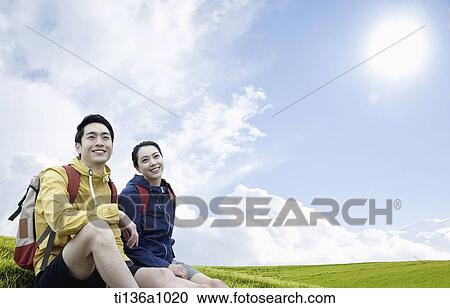 a couple sitting on a grass field View Large Photo Image Stock Image - a couple sitting on a grass field. Fotosearch