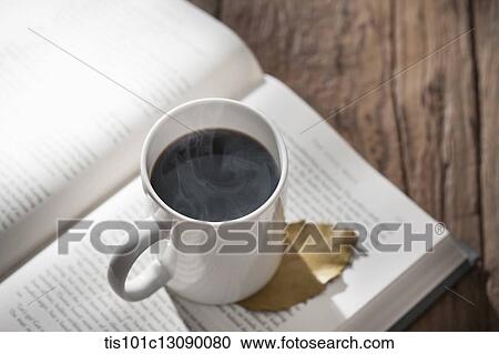 a cup of coffee on a book on wooden surface View Large Photo Image Stock Image - a cup of coffee on a book on wooden surface. Fotosearch