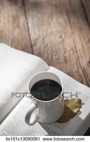 a cup of coffee on a book on wooden surface View Large Photo Image Stock Image - a cup of coffee on a book on wooden surface. Fotosearch