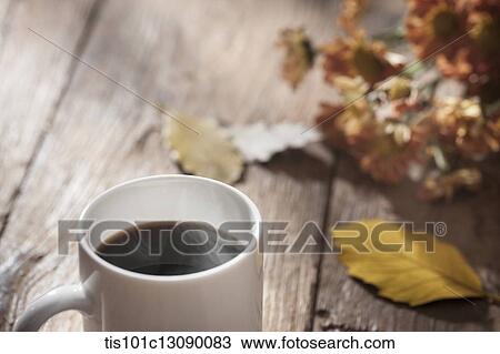 a cup of coffee on wooden surface with autumn flowers View Large Photo Image Stock Image - a cup of coffee on wooden surface with autumn flowers. Fotosearch