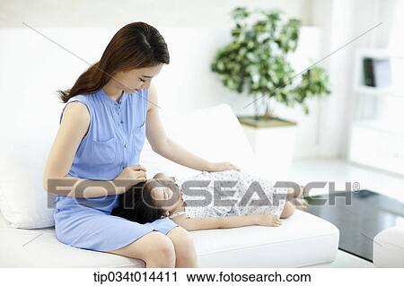 Stock Image - a daughter lying on mother's thighs. Fotosearch