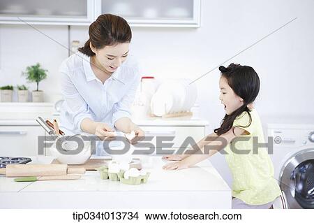 Picture - a daughter watching mother cooking. Fotosearch