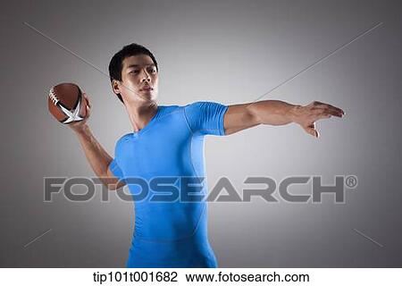 Stock Image - a fit man in blue shirt about to throw a rugby ball. Fotosearch