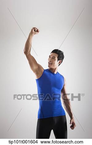 Picture - a fit man in blue shirt posing with hands. Fotosearch