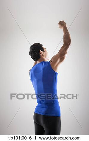 Stock Image - a fit man in blue shirt posing with hands. Fotosearch