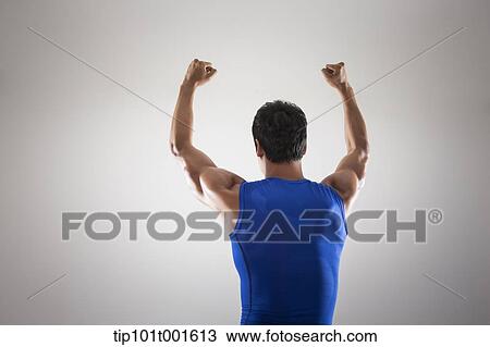 Stock Image - a fit man in blue shirt posing with hands. Fotosearch