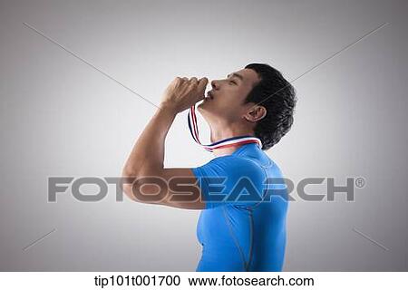 a fit man in blue shirt posing with gold medal around his neck View Large Photo Image Stock Image - a fit man in blue shirt posing with gold medal around his neck. Fotosearch