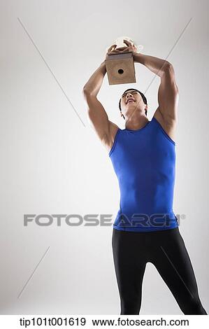 Stock Photo - a fit man in blue shirt posing with trophy. Fotosearch