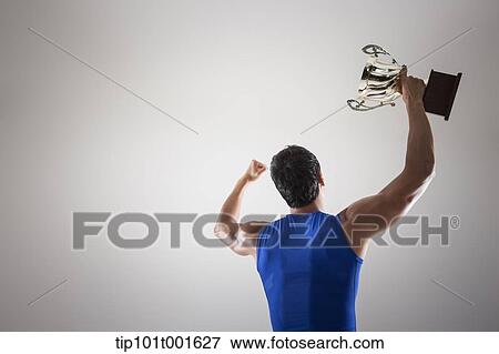 a fit man in blue shirt posing with trophy View Large Photo Image Stock Photo - a fit man in blue shirt posing with trophy. Fotosearch