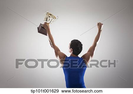 a fit man in blue shirt posing with trophy View Large Photo Image Stock Photo - a fit man in blue shirt posing with trophy. Fotosearch