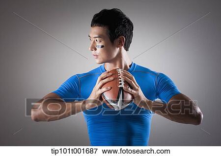Stock Photo - a fit man in blue shirt posing with rugby ball. Fotosearch