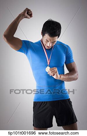 a fit man in blue shirt posing with gold medal around his neck View Large Photo Image Stock Photograph - a fit man in blue shirt posing with gold medal around his neck. Fotosearch