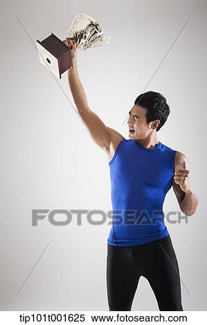 a fit man in blue shirt posing with trophy View Large Photo Image Stock Photography - a fit man in blue shirt posing with trophy. Fotosearch