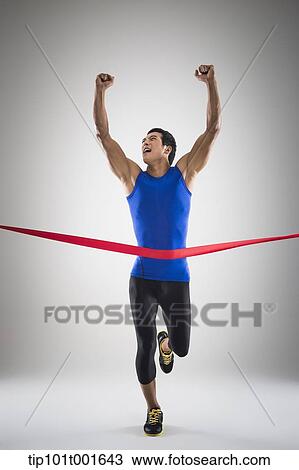 Stock Image - a fit man in blue shirt running to a finishing line. Fotosearch