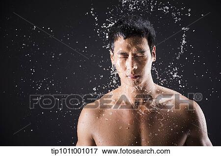 Stock Photo - a fit man posing in black background with water splash. Fotosearch