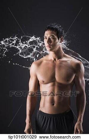 Stock Photo - a fit man posing in black background with water splash. Fotosearch