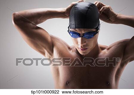 a fit man putting on swimming hat View Large Photo Image Stock Image - a fit man putting on swimming hat. Fotosearch