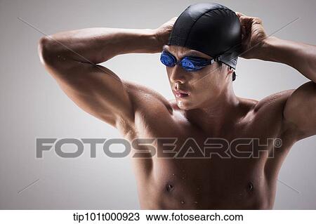 Stock Image - a fit man putting on swimming hat. Fotosearch