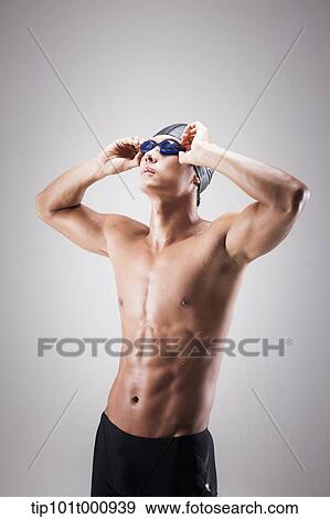 Stock Photo - a fit man with swimming goggle and hat posing. Fotosearch