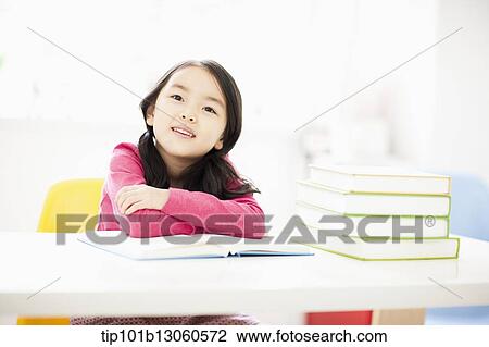 a girl at desk next to a pile of books View Large Photo Image Stock Image - a girl at desk next to a pile of books. Fotosearch