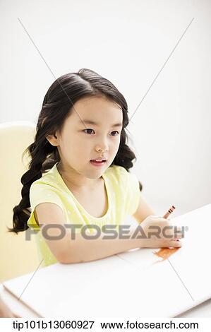 Stock Photo - a girl drawing on a sketch book with crayon. Fotosearch