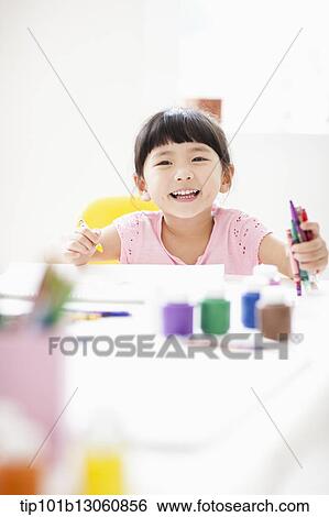 Stock Photograph - a girl drawing on a sketch book with crayon. Fotosearch