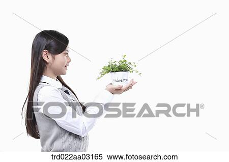 a girl dressed as a student holding a plant View Large Photo Image Stock Photography - a girl dressed as a student holding a plant. Fotosearch