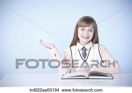 a girl dressed as a student sitting at a desk with a book View Large Photo Image Picture - a girl dressed as a student sitting at a desk with a book. Fotosearch