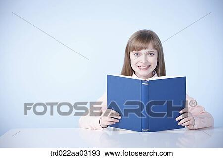 a girl dressed as a student sitting at a desk with a book View Large Photo Image Stock Image - a girl dressed as a student sitting at a desk with a book. Fotosearch
