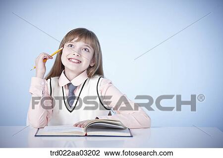 a girl dressed as a student sitting at a desk with a book View Large Photo Image Stock Image - a girl dressed as a student sitting at a desk with a book. Fotosearch