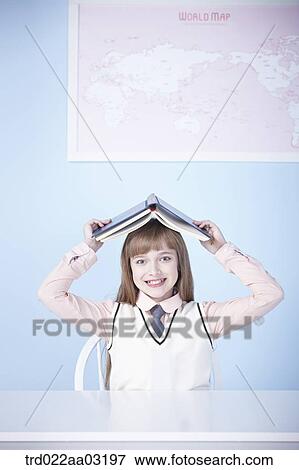 a girl dressed as a student sitting at a desk with a book View Large Photo Image Stock Photo - a girl dressed as a student sitting at a desk with a book. Fotosearch