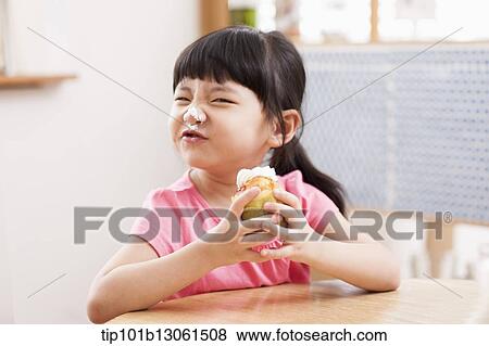 Stock Photo - a girl eating a cupcake. Fotosearch
