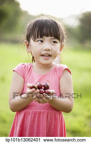 Stock Image - a girl holding a bunch of cherries. Fotosearch