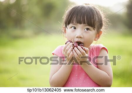 Stock Photography - a girl holding a bunch of cherries. Fotosearch