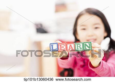 Stock Photograph - a girl holding toy cubes saying learn. Fotosearch