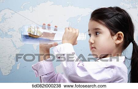 a girl looking into a glass bottle with a ship inside View Large Photo Image Stock Photo - a girl looking into a glass bottle with a ship inside . Fotosearch