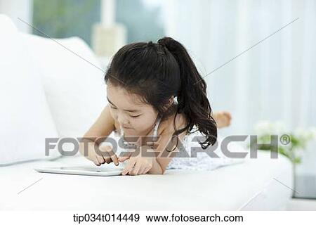 a girl lying on a couch using tablet PC View Large Photo Image Stock Photo - a girl lying on a couch using tablet PC . Fotosearch