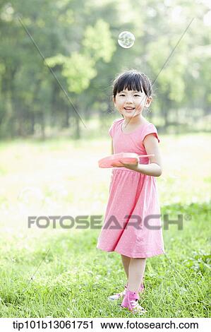 Stock Image - a girl making soap bubbles. Fotosearch