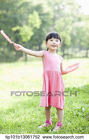 Stock Image - a girl making soap bubbles. Fotosearch